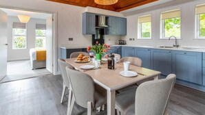 Una cocina moderna con armarios azules, techo de madera y un comedor con mesa para dos.