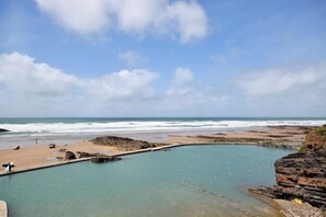 Eine Küstenlandschaft mit Schwimmbad, Strand und Klippen.