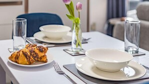 Un tavolo da pranzo con un croissant, una ciotola, un vaso con fiori e dei bicchieri.