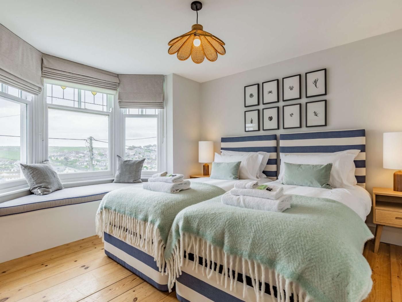 Une chambre d’hôtel avec un grand lit, deux tables de chevet, une fenêtre avec vue et un luminaire suspendu.