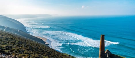 Un paysage côtier avec une structure en pierre, une plage et des vagues de l’océan.