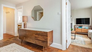 Ein modernes Wohnzimmer mit einem Holzkasten, einem großen Spiegel und einem Fernseher.