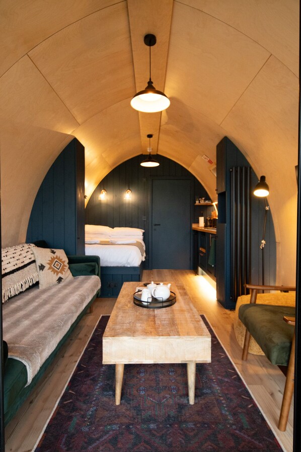 A cozy interior with a wooden table, a sofa, a bed, and a bench.