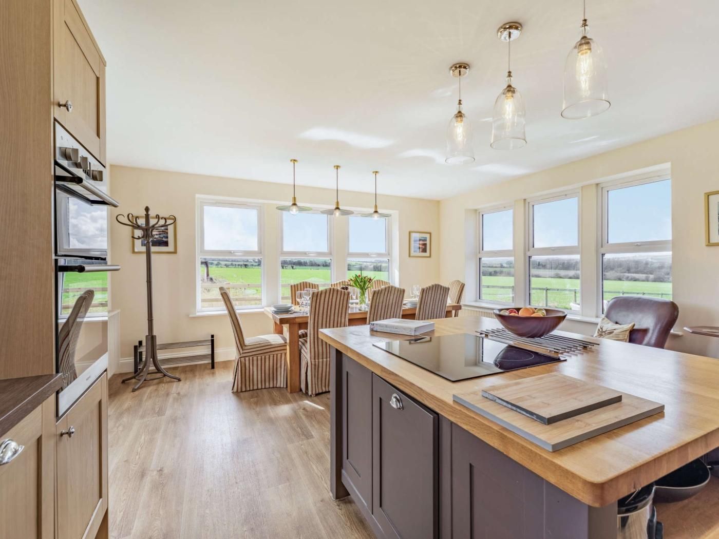 A modern kitchen with a central island, large windows, and a view of the outdoors.