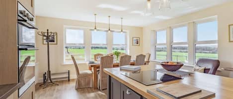 A modern kitchen with a central island, large windows, and a view of the outdoors.