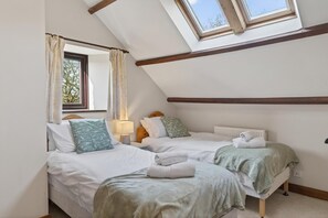 Ein Schlafzimmer mit zwei Betten, einem Oberlicht, einem Fenster und einer Heizkörper.