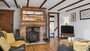 A living room with a brick fireplace, wooden beams, a television, and a sofa. - 4 Bed in Newport (oc-88913) (Porchfield)