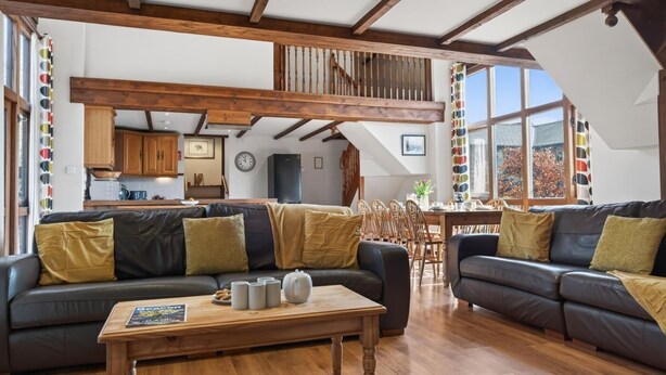 A spacious living area with two sofas, a wooden coffee table, and a dining table. - 4 Bed in Newport (oc-88913) (Porchfield)