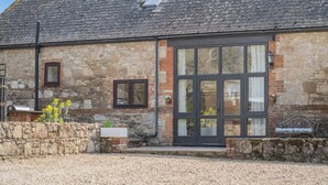 A stone building with a large glass door, a small window, and a metal bench. - 4 Bed in Newport (oc-88913) (Porchfield)