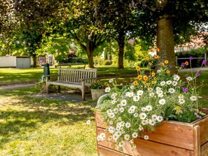 A wooden planter box with white flowers and a bench in a park. - 3 Bed in Budleigh Salterton (oc-88004) (Otterton)