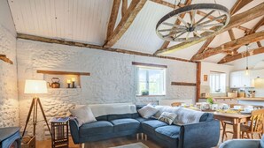 Een gezellige woonkamer met een stenen muur, een blauwe bank, een houten tafel en een rustiek plafond.