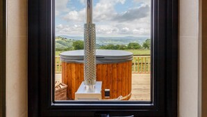 A hot tub on a wooden deck with a view of a landscape. - 1 Bed in Abergavenny (oc-88015) (Llanover)