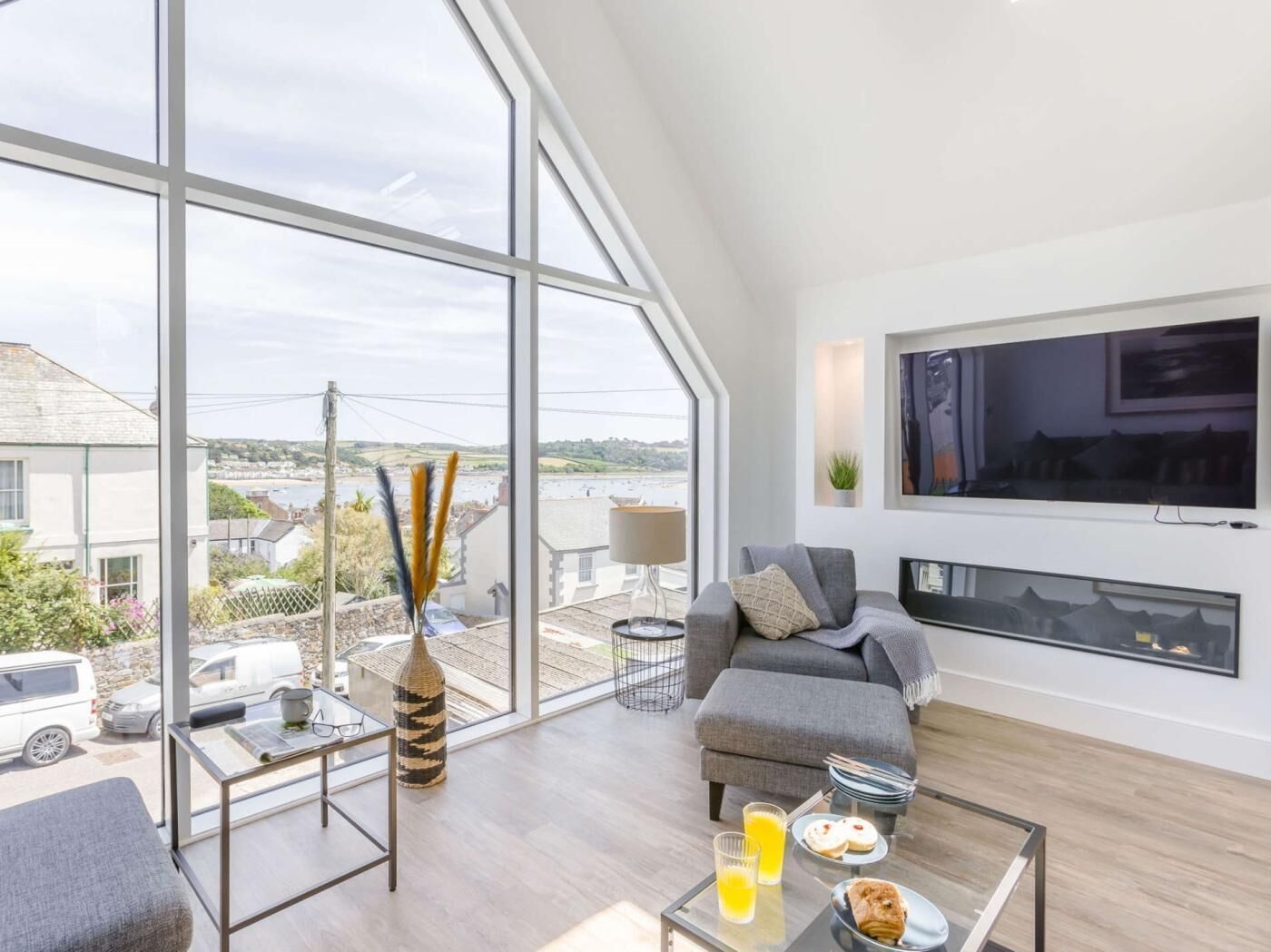 A modern living room with a large window, a sofa, a coffee table, and a TV.
