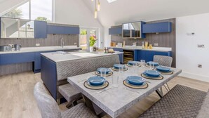 Una cocina moderna con una isla grande, electrodomésticos integrados y un comedor con mesa para seis.