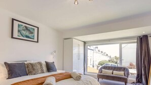 Un dormitorio con una cama grande, un banco, una ventana con vistas y un cuadro enmarcado en la pared.