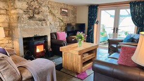 Ein gemütliches Wohnzimmer mit Steinwand, Kamin, Ledersofas und einem Holztisch.