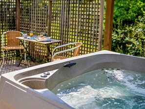 A hot tub with a control panel, surrounded by a wooden fence and outdoor furniture. - 2 Bed in Saltash (oc-88308) (Notter)