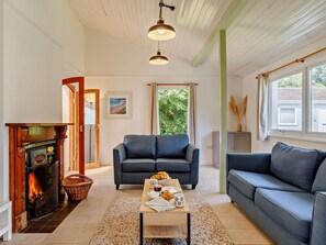 Una sala de estar con chimenea, dos sofás, una mesa de centro con alimentos para el desayuno y un cuadro en la pared.