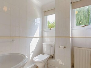 A bathroom with white tiles, a bathtub, a toilet, a window with a view of greenery, and a radiator. - 2 Bed in Saltash (oc-88308) (Notter)