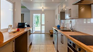 A modern kitchen with a wooden countertop, stainless steel appliances, and a view through the glass door. - 2 Bed in Saltash (oc-88308) (Notter)
