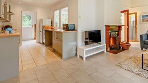 A modern kitchen with a built-in microwave, a TV on a white stand, and a fireplace. - 2 Bed in Saltash (oc-88308) (Notter)