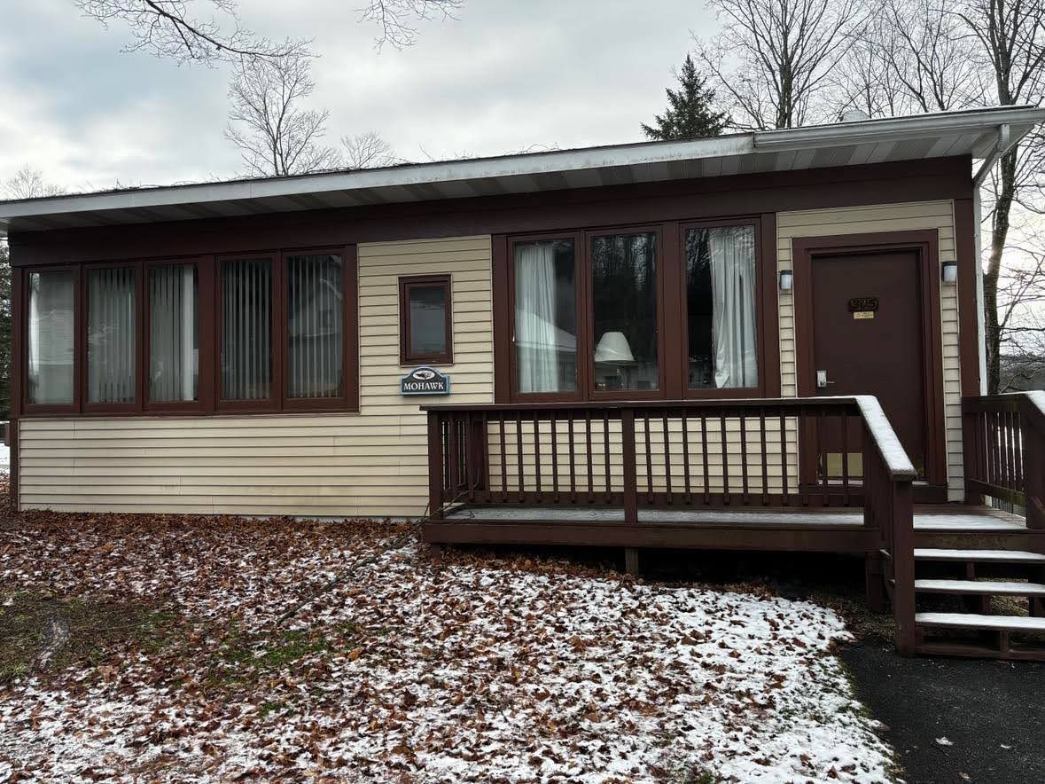 A single-story mobile home with a front porch, a door, and a window.