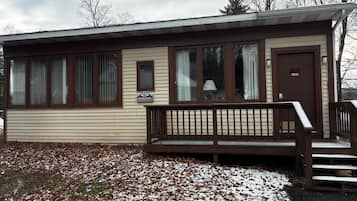 A single-story mobile home with a front porch, a door, and a window.