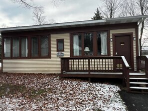 A single-story mobile home with a front porch, a door, and a window.
