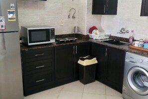 A compact kitchen with a microwave, sink, and washing machine. - AMWAJ - 2 bedroom chalet with poolview (Marsa Matrouh Governorate)