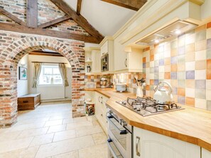A kitchen with a brick archway, a tiled backsplash, and a gas stove. - 3 Bed in Alnwick (oc-88231) (Longhoughton)
