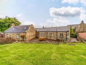 A stone house with a grassy yard and a wooden table. - 3 Bed in Alnwick (oc-88231) (Longhoughton)