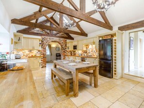 A spacious kitchen with exposed wooden beams, a brick archway, and a large dining table set for six. - 3 Bed in Alnwick (oc-88231) (Longhoughton)