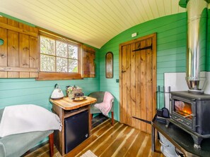 Ein gemütliches Blockhaus-Interieur mit Holzofen, einem Fenster mit Blick und einem kleinen Tisch mit Gegenständen darauf.