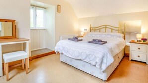 Une chambre à coucher avec un lit, une table de chevet, une lampe et une fenêtre.