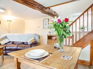 A wooden dining table with a white bowl and a wine glass, a leather sofa with a blanket, and a wooden staircase. - 1 Bed in Bala (oc-88450) (Llandderfel)