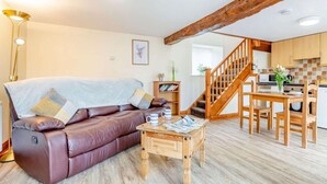 Un salon avec un canapé en cuir, une table basse en bois et un escalier menant à la cuisine.