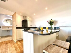 A modern kitchen with a central island, a sink, and a countertop with two glasses of orange juice.