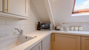 Eine Küche mit weißen Fliesen, einem Spülbecken, einem Toaster und einem Wasserkocher.