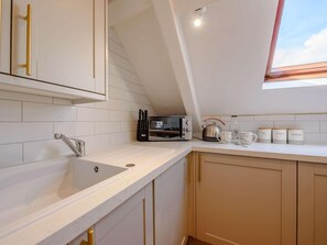 A kitchen with white tiles, a sink, a toaster, and a kettle. - 1 Bed in Tenby (oc-88504) (Tenby)