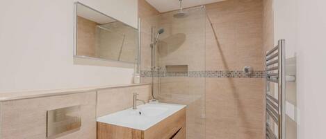 Een moderne badkamer met een douche, een wastafel en een spiegel.