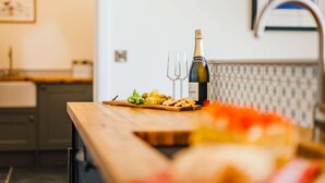 A kitchen counter with a bottle of wine, glasses, and food items.