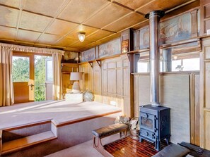A cozy room with a large bed, a wooden floor, a fireplace, and a window with curtains. - 4 Bed in East Cowes (oc-88655) (East Cowes)