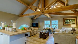 Un ampio loft con travi a vista in legno, un'accogliente zona salotto, un tavolo da pranzo e un televisore.