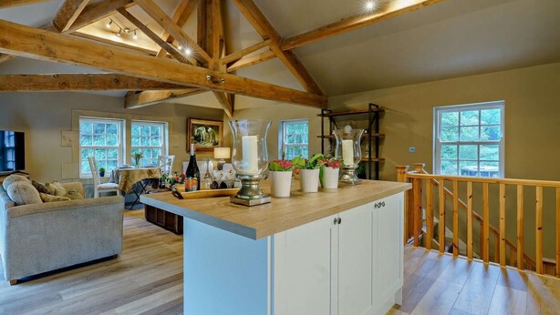 Un'ampia zona giorno con soffitto in legno, un'isola centrale con mobili, un divano e un tavolo da pranzo.