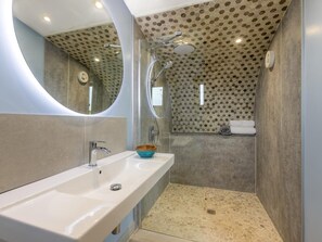 Ein Badezimmer mit großem Spiegel, Waschbecken, Dusche und Wandgestaltung mit sechseckischen Fliesen.