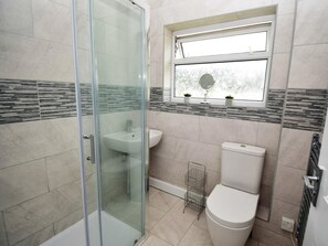 Une salle de bain avec une douche à parois de verre, un lavabo, des toilettes et une fenêtre avec un miroir.