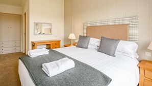 Ein Schlafzimmer mit Bett, Nachttischen, einem Schreibtisch, einem Spiegel und einem Kleiderschrank.