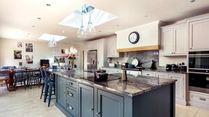Una cucina moderna con una grande isola, mobili bianchi e un orologio a parete.