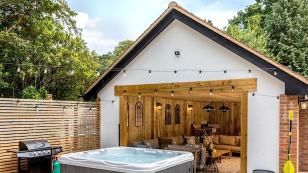 Un'area esterna coperta con vasca idromassaggio, barbecue e posti a sedere.