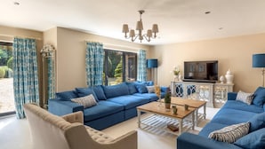 Un soggiorno con un divano blu, una poltrona beige, un tavolino da caffè e una televisione.